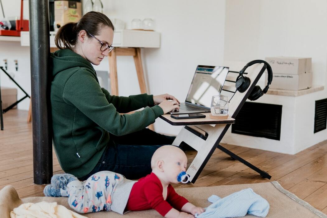 mère travaillant sur un ordinateur portable tout en surveillant son bébé